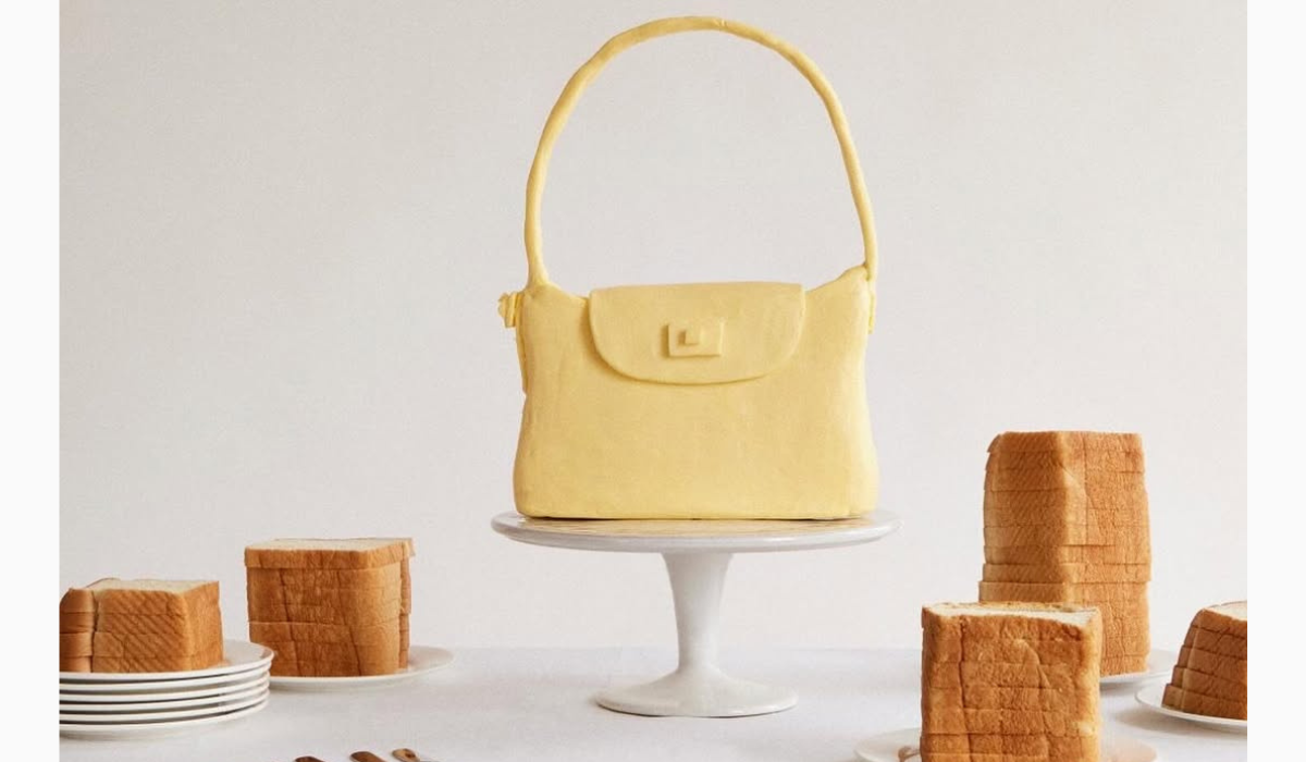 A creative visual from J.Crew featuring a replica of their handbag sculpted entirely out of butter. The bag is displayed on a cake stand, surrounded by sliced bread on plates.